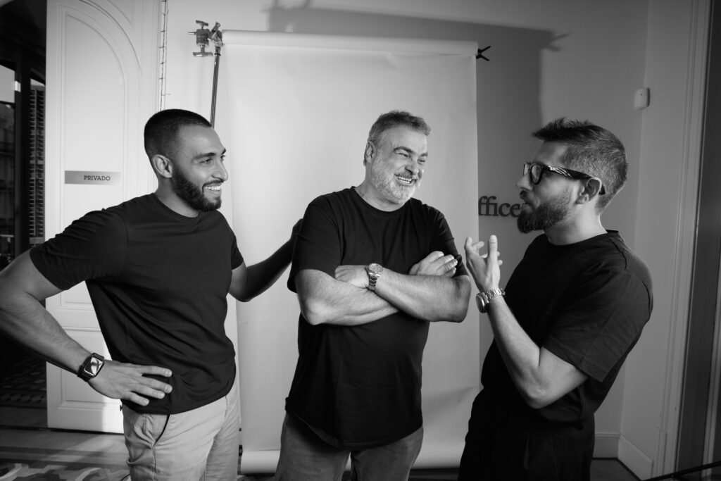 Black and white photo of three Gusto founders smiling and talking in a relaxed studio setting.